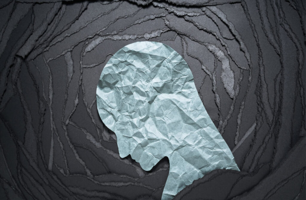 a head shape cut out of paper and wrinkled on a background of torn paper to represent anxiety