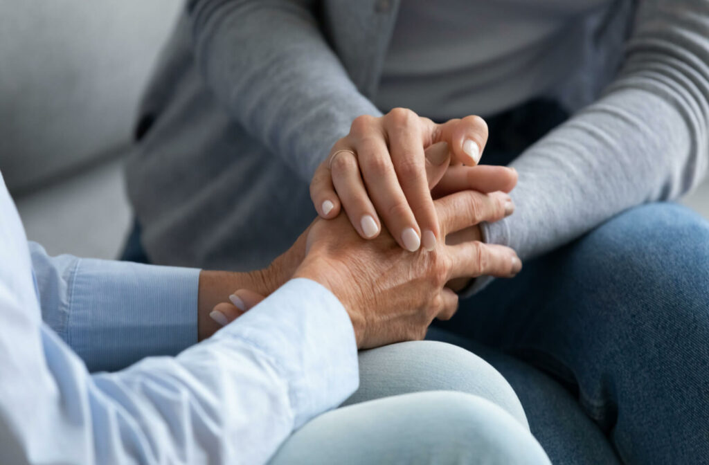a young person holds the hands of a senior woman experiencing memory loss