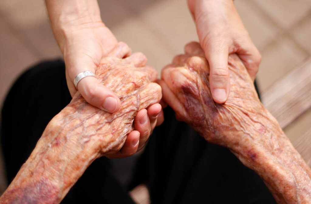 a pair of young hands holds a pair of senior hands in support