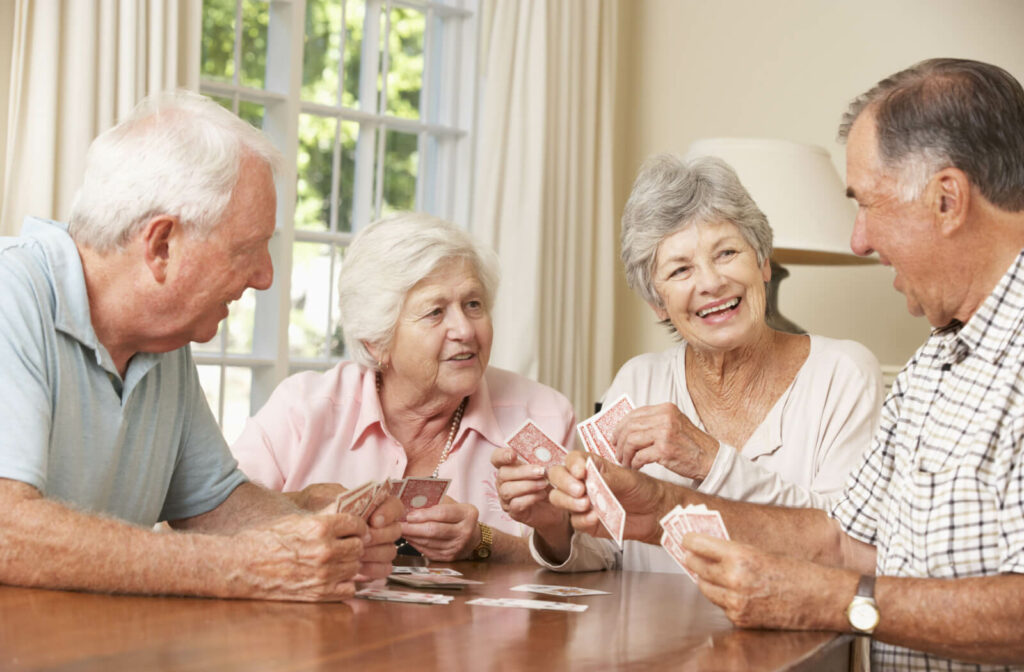 group of seniors sit around a table while playing cards