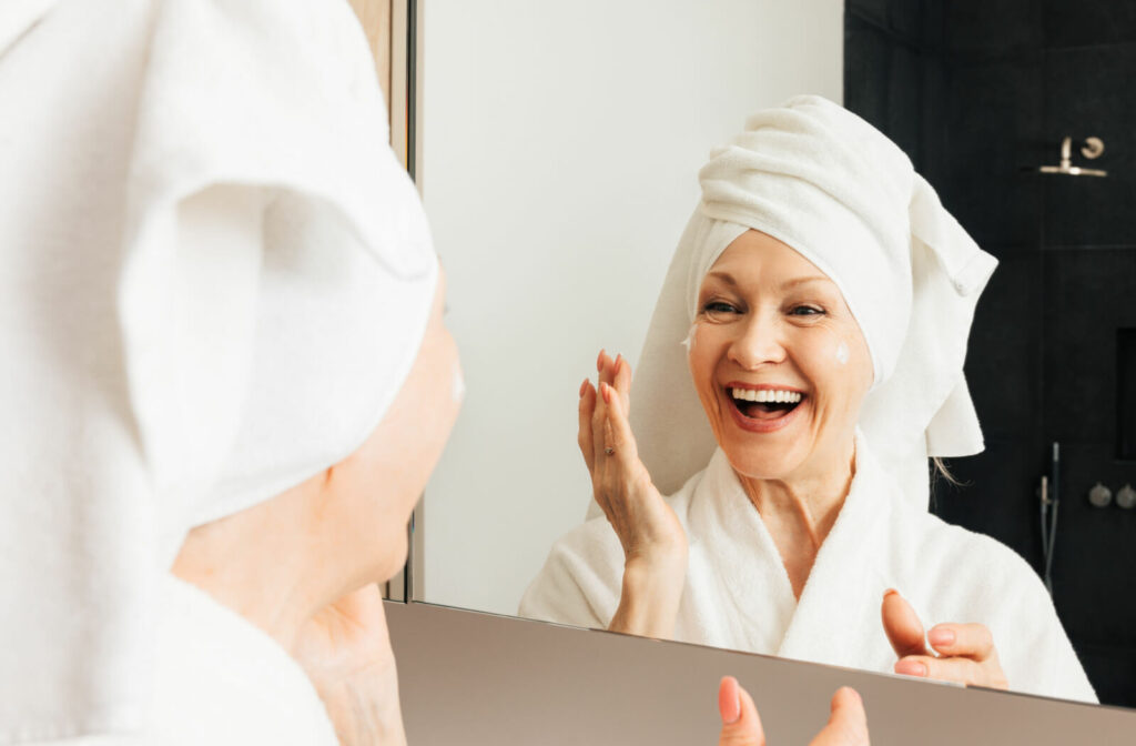 A senior woman applying face cream after a bath.
