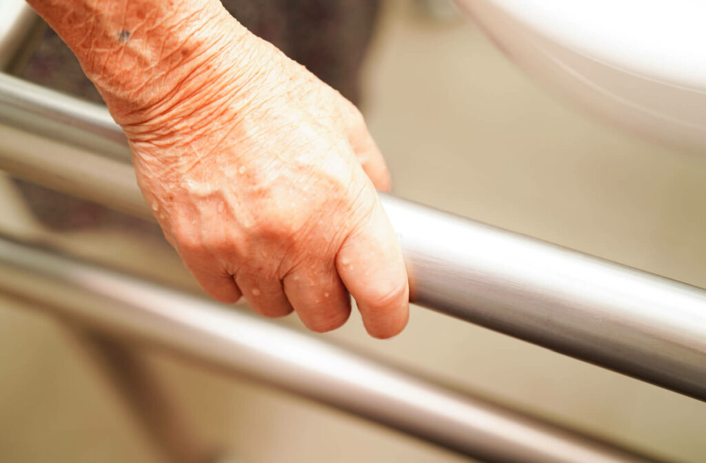A patient woman is gripping a safety handrail inside the bathroom of a memory care facility.